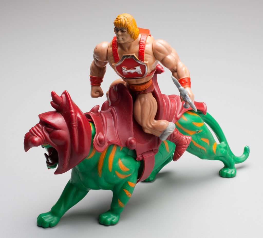 The moulded He-Man figure has a muscular body, blonde hair and wears a red chest plate with the letter 'H' strapped to his body. He wears red briefs, orange belt, orange wrist bands and long grey and red boots. He carries a grey double-edged broad axe in one hand and has a yellow sword and silver shield. The moulded green plastic Battle Cat figure features orange stripes and is modelled in a stalking position, mouth open and teeth bared in an aggressive manner. His head is covered with a red armoured helmet and on his back is a large red saddle.